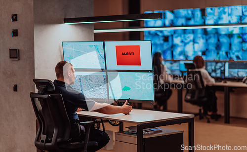 Image of Group of Security data center operators working in a CCTV monitoring room looking on multiple monitors.Officers Monitoring Multiple Screens for Suspicious Activities