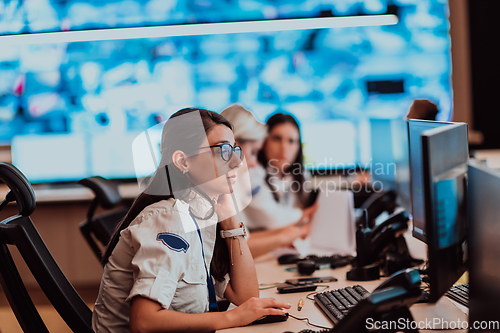 Image of Group of Security data center operators working in a CCTV monitoring room looking on multiple monitors.Officers Monitoring Multiple Screens for Suspicious Activities