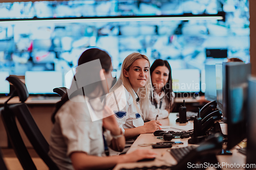 Image of Group of Security data center operators working in a CCTV monitoring room looking on multiple monitors.Officers Monitoring Multiple Screens for Suspicious Activities