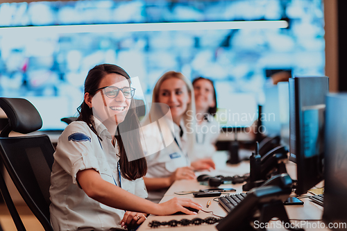 Image of Group of Security data center operators working in a CCTV monitoring room looking on multiple monitors.Officers Monitoring Multiple Screens for Suspicious Activities