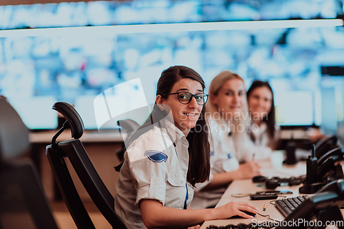 Image of Group of Security data center operators working in a CCTV monitoring room looking on multiple monitors.Officers Monitoring Multiple Screens for Suspicious Activities