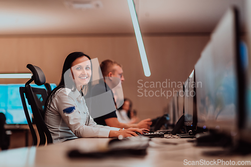 Image of Group of Security data center operators working in a CCTV monitoring room looking on multiple monitors.Officers Monitoring Multiple Screens for Suspicious Activities