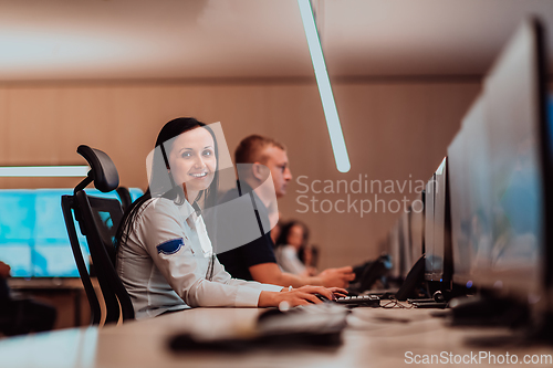 Image of Group of Security data center operators working in a CCTV monitoring room looking on multiple monitors.Officers Monitoring Multiple Screens for Suspicious Activities