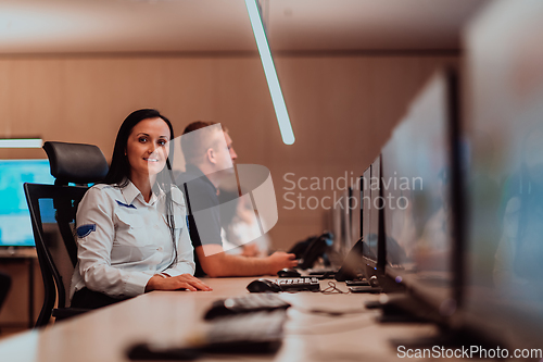 Image of Group of Security data center operators working in a CCTV monitoring room looking on multiple monitors.Officers Monitoring Multiple Screens for Suspicious Activities