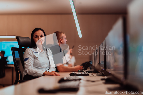 Image of Group of Security data center operators working in a CCTV monitoring room looking on multiple monitors.Officers Monitoring Multiple Screens for Suspicious Activities