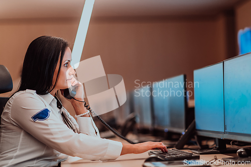 Image of Female security operator working in a data system control room offices Technical Operator Working at workstation with multiple displays, security guard working on multiple monitors