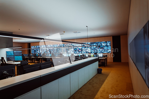 Image of Group of Security data center operators working in a CCTV monitoring room looking on multiple monitors.Officers Monitoring Multiple Screens for Suspicious Activities