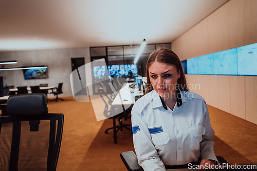 Image of Female security operator working in a data system control room offices Technical Operator Working at workstation with multiple displays, security guard working on multiple monitors