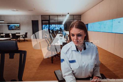 Image of Female security operator working in a data system control room offices Technical Operator Working at workstation with multiple displays, security guard working on multiple monitors