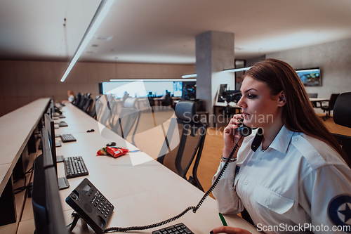 Image of Female security operator working in a data system control room offices Technical Operator Working at workstation with multiple displays, security guard working on multiple monitors