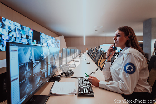 Image of Female security operator working in a data system control room offices Technical Operator Working at workstation with multiple displays, security guard working on multiple monitors