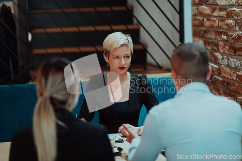 Image of Happy businesspeople smiling cheerfully during a meeting in a coffee shop. Group of successful business professionals working as a team in a multicultural workplace.