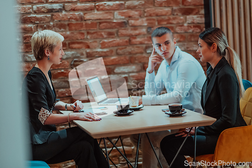 Image of Happy businesspeople smiling cheerfully during a meeting in a coffee shop. Group of successful business professionals working as a team in a multicultural workplace.