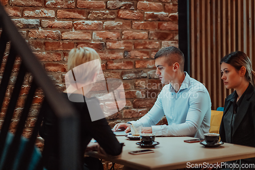 Image of Happy businesspeople smiling cheerfully during a meeting in a coffee shop. Group of successful business professionals working as a team in a multicultural workplace.