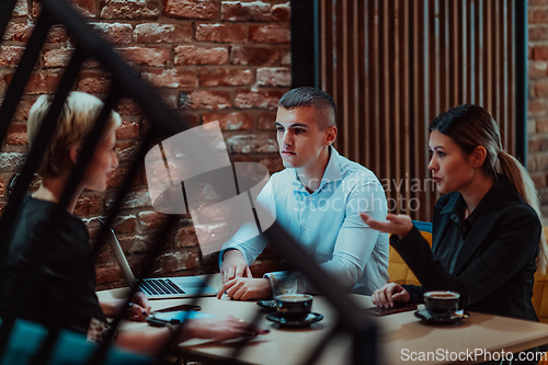 Image of Happy businesspeople smiling cheerfully during a meeting in a coffee shop. Group of successful business professionals working as a team in a multicultural workplace.