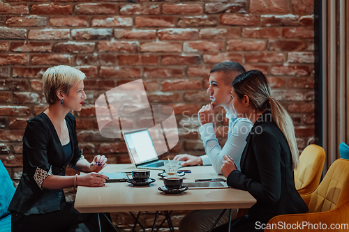 Image of Happy businesspeople smiling cheerfully during a meeting in a coffee shop. Group of successful business professionals working as a team in a multicultural workplace.