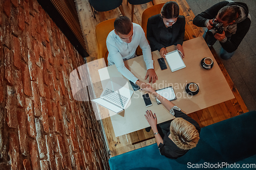 Image of Top view photo of business shaking hands, finishing up meeting. Successful businesspeople handshaking after good deal