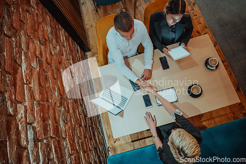 Image of Top view photo of business shaking hands, finishing up meeting. Successful businesspeople handshaking after good deal