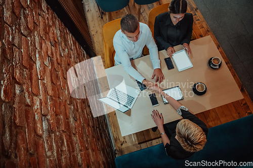 Image of Top view photo of business shaking hands, finishing up meeting. Successful businesspeople handshaking after good deal