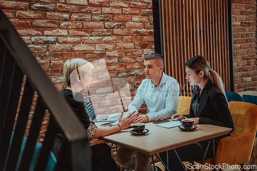 Image of Happy businesspeople smiling cheerfully during a meeting in a coffee shop. Group of successful business professionals working as a team in a multicultural workplace.