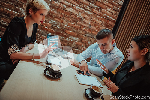 Image of Happy businesspeople smiling cheerfully during a meeting in a coffee shop. Group of successful business professionals working as a team in a multicultural workplace.