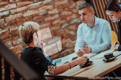 Image of Happy businesspeople smiling cheerfully during a meeting in a coffee shop. Group of successful business professionals working as a team in a multicultural workplace.