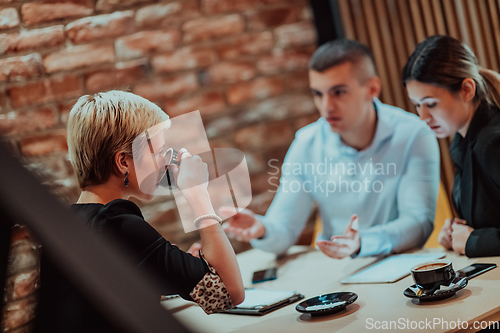 Image of Happy businesspeople smiling cheerfully during a meeting in a coffee shop. Group of successful business professionals working as a team in a multicultural workplace.