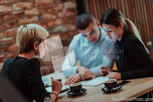 Image of Happy businesspeople smiling cheerfully during a meeting in a coffee shop. Group of successful business professionals working as a team in a multicultural workplace.