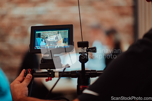 Image of Behinde The Scenes. A cameraman records a business meeting that is streamed on TV channels