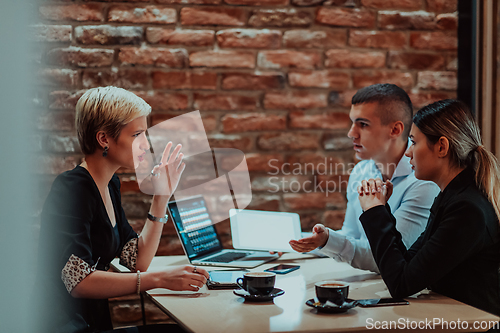 Image of Happy businesspeople smiling cheerfully during a meeting in a coffee shop. Group of successful business professionals working as a team in a multicultural workplace.