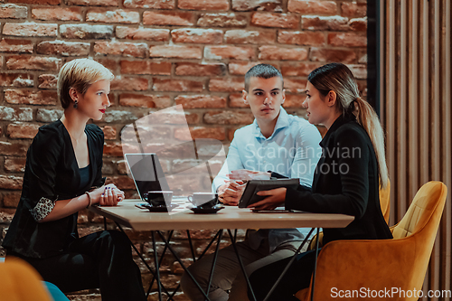 Image of Happy businesspeople smiling cheerfully during a meeting in a coffee shop. Group of successful business professionals working as a team in a multicultural workplace.