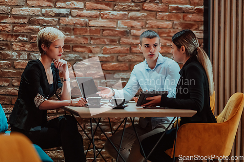 Image of Happy businesspeople smiling cheerfully during a meeting in a coffee shop. Group of successful business professionals working as a team in a multicultural workplace.