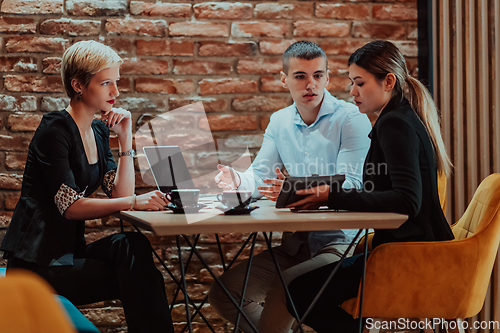 Image of Happy businesspeople smiling cheerfully during a meeting in a coffee shop. Group of successful business professionals working as a team in a multicultural workplace.