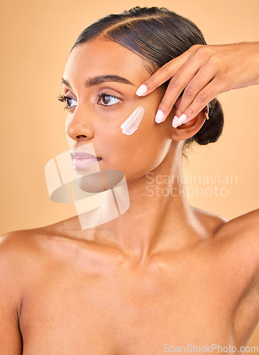 Image of Face, skincare idea and woman with cream in studio isolated on a brown background. Dermatology, cosmetics and thinking Indian female model with lotion, beauty creme or moisturizer for skin health.