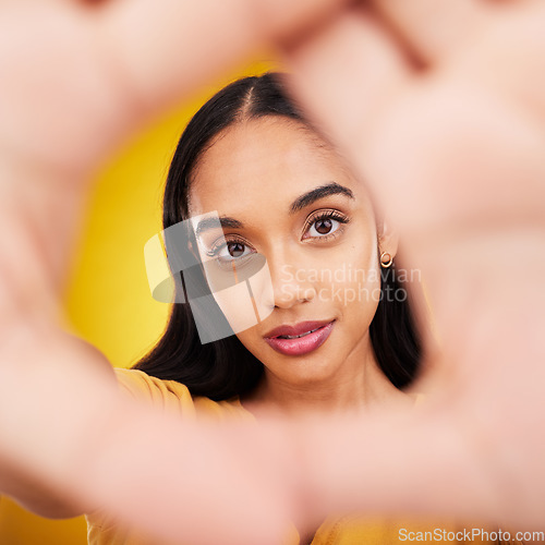 Image of Hands, gesture and portrait of a beautiful woman isolated on a yellow background in a studio. Looking, perspective and the face of a girl in a hand frame for creativity, look through and focus