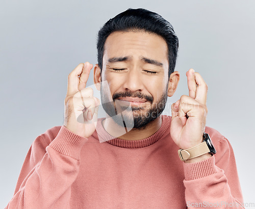 Image of Wish, fingers crossed and praying with man in studio for good luck, promotion and announcement. Lottery, winner and hope with male isolated on white background for nervous, worry and belief gesture