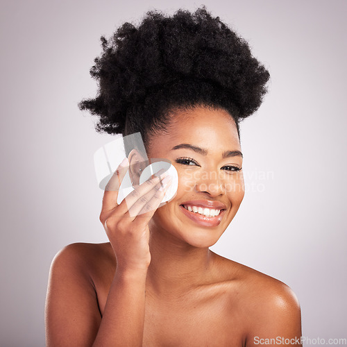 Image of Black woman, cotton pad and skincare in studio with cleaning, makeup removal and happy by background. Young model, wipe and clean face for natural glow, wellness and cosmetic health with self care