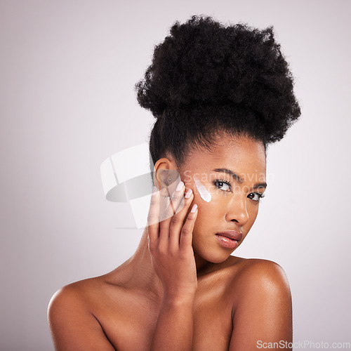 Image of Black woman, face and moisturizer cream for skincare beauty or cosmetics against a gray studio background. Portrait of African American female applying moisturizing creme, lotion or facial product