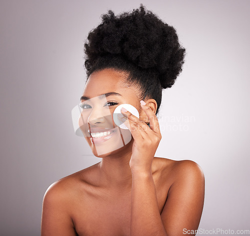 Image of Black woman, cotton and skincare in studio with cleaning, makeup removal and happy by background. Young model, beauty or wipe to clean face for natural glow, wellness or cosmetic health for self care