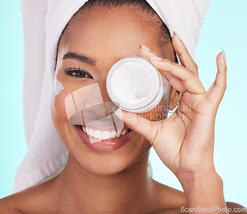 Image of Black woman, jar and cream in studio portrait with smile for skincare, wellness or self care by blue background. Girl, african and model with product by eye for natural skin glow, beauty or cosmetics