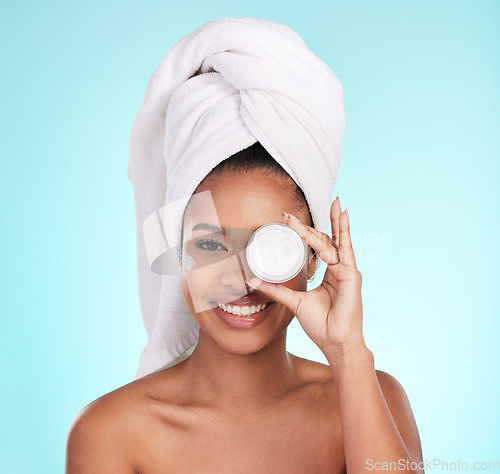 Image of Black woman, jar and skin cream in studio portrait with smile for skincare, wellness or self care by blue background. Girl, african and model with product by eye for natural glow, beauty or cosmetics