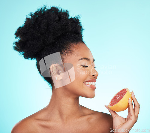 Image of Grapefruit, skincare and woman smile with fruit for beauty, wellness and detox healthcare. Isolated, blue background and studio with a young female feeling happy from healthy food with vitamin c