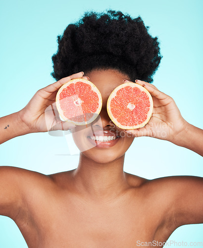 Image of Black woman, face and hands with grapefruit for skincare nutrition, beauty or vitamin C against a blue studio background. Portrait of African female smiling with fruit for natural health and wellness