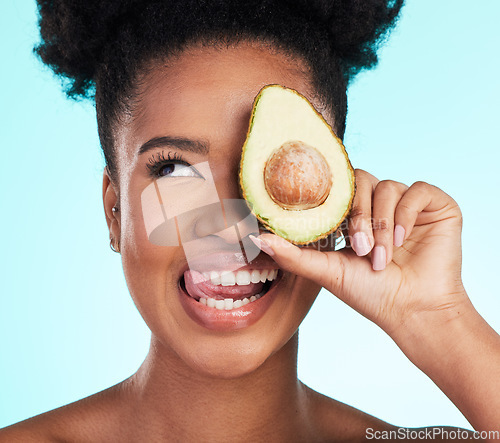 Image of Avocado, woman tongue out and happy face of a young model with skincare, fruit and wellness for diet. Isolated, blue background and studio with a silly person with beauty, cosmetics and healthy food