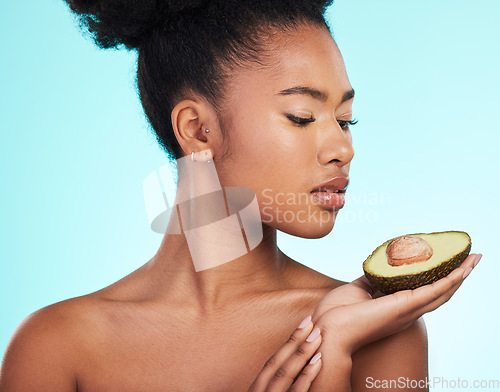 Image of Avocado, woman and beauty of a young model with skincare, fruit and wellness for diet. Isolated, blue background and studio with a person with facial, cosmetics and healthy food for skin glow