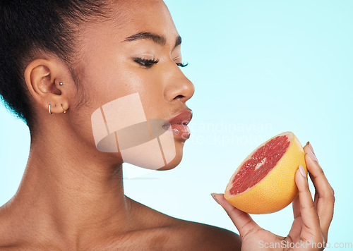 Image of Grapefruit, woman and profile of a young model with skincare, fruit and wellness for diet. Isolated, blue background and studio with a person with beauty, cosmetics and healthy food for skin glow