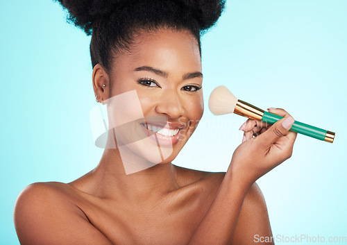 Image of Black woman, brush and makeup in studio with smile for wellness, cosmetics or youth by blue background. Model, girl and african with foundation, powder and happy for skincare, beauty and healthy glow