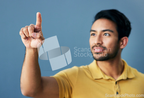 Image of Finger, pointing and asian man with invisible hologram in studio with mockup against blue background. Interface, hand and creative male entrepreneur with advertising, marketing or idea while isolated