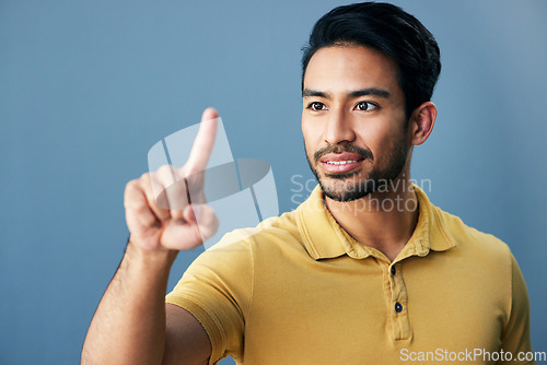 Image of Pointing, finger and asian man with invisible hologram in studio with mockup against blue background. Interface, hand and creative male entrepreneur with advertising, marketing or idea while isolated