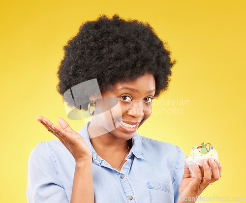 Image of Young black woman, cupcake dessert and studio with temptation, cheat diet and junk food by yellow background. African model, cake and choice for unhealthy, nutrition and sweets with meal in portrait